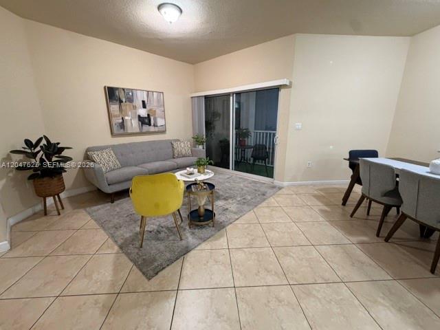 A living room with a gray sofa, yellow accent chair, and tile flooring — DORAL, FL