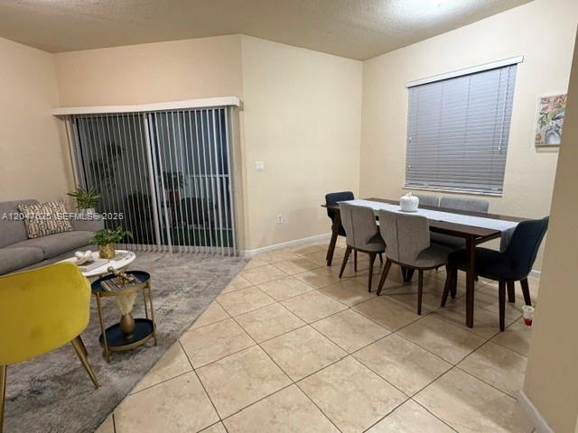 A living and dining area features tile flooring, a sliding glass door, and neutral walls — DORAL, FL