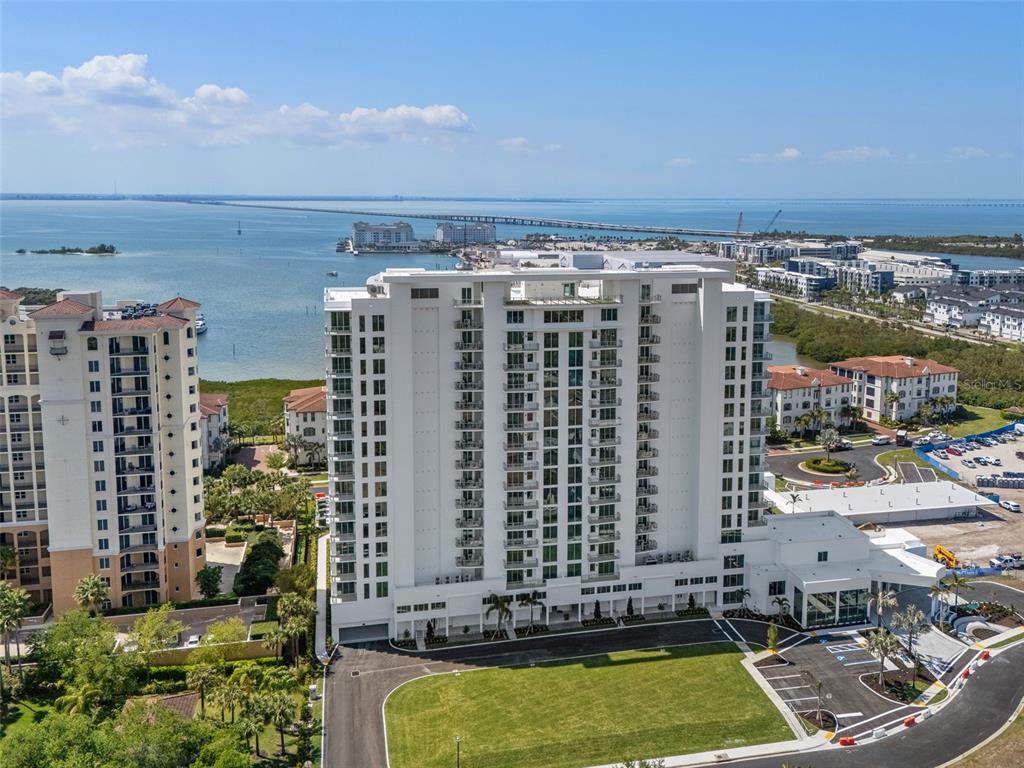 An aerial view shows a tall white apartment building next to a bay and bridge — 5713 BOWEN DANIEL DRIVE UNIT 903, TAMPA, FL