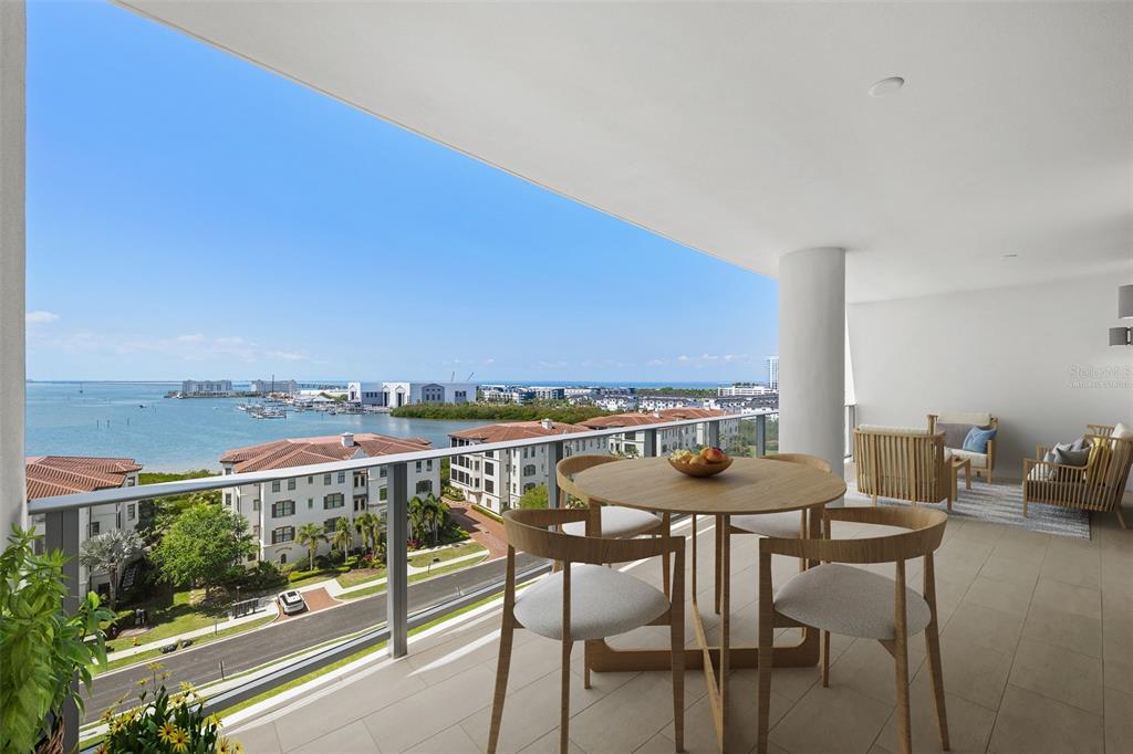 A spacious balcony features a dining set, lounge seating, and a view of the water — 5713 BOWEN DANIEL DRIVE UNIT 903, TAMPA, FL