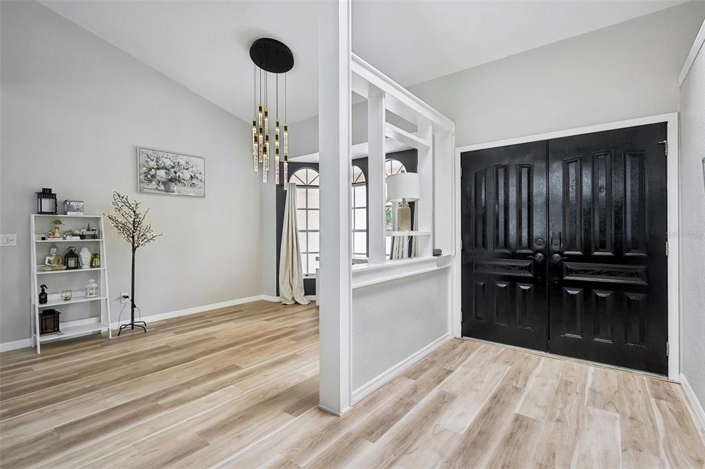 An entryway features light wood flooring, a white room divider, and a black double door — 1260 MASADA LANE, SPRING HILL, FL