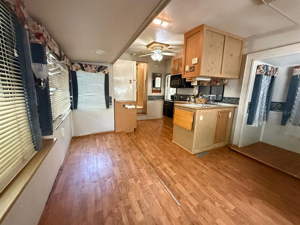 An interior view of a kitchen and living area with wood-look flooring and wooden cabinets — 3000 CLARCONA ROAD UNIT 419, APOPKA, FL