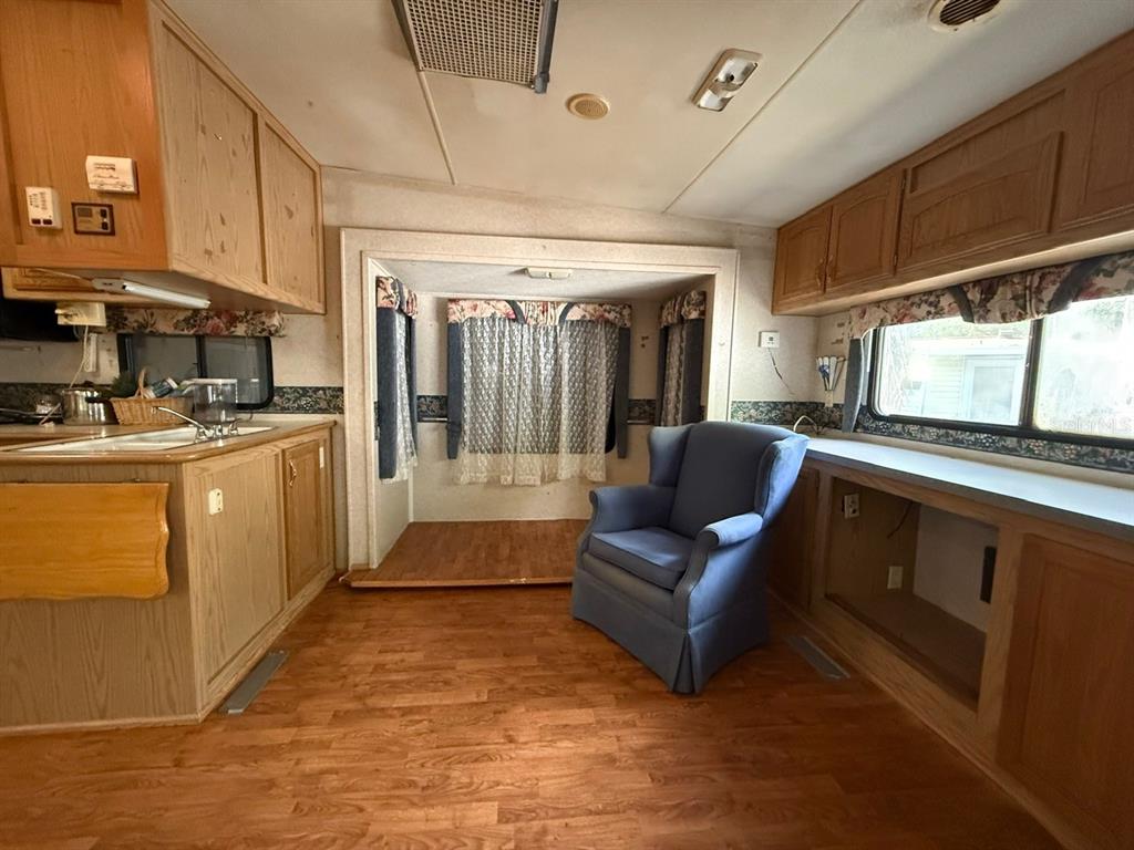 A room in a recreational vehicle features wood-look flooring, light wood cabinetry, and a blue armchair — 3000 CLARCONA ROAD UNIT 419, APOPKA, FL