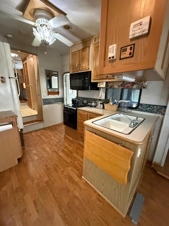 A kitchen in a recreational vehicle features wood cabinetry, a sink, and a microwave — 3000 CLARCONA ROAD UNIT 419, APOPKA, FL