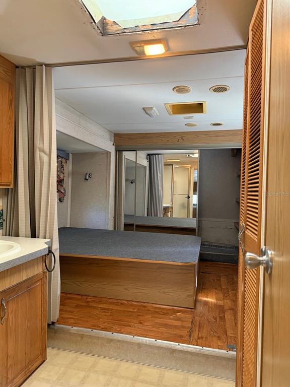 A bedroom with a raised bed platform, wood flooring, and mirrored closet doors — 3000 CLARCONA ROAD UNIT 419, APOPKA, FL