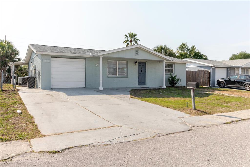 A single-story house with a light green exterior, a garage, and a concrete driveway — 9803 RICHWOOD LANE, PORT RICHEY, FL