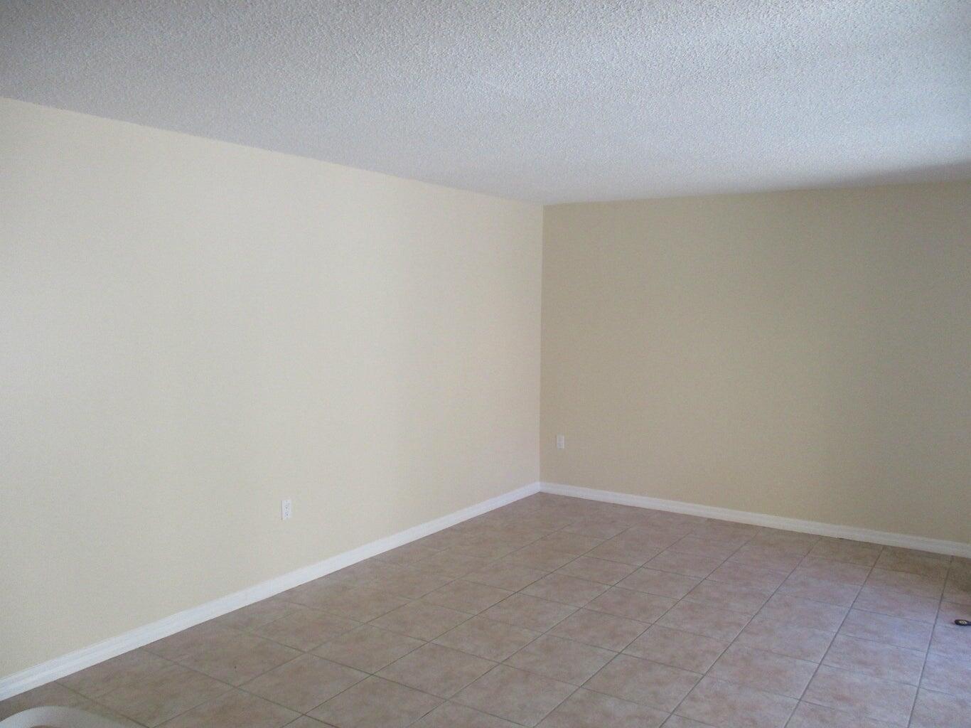An empty room with beige walls, white baseboards, and light-colored tile flooring — 825 Center Street # 3c, Jupiter FL 33458, JUPITER, FL