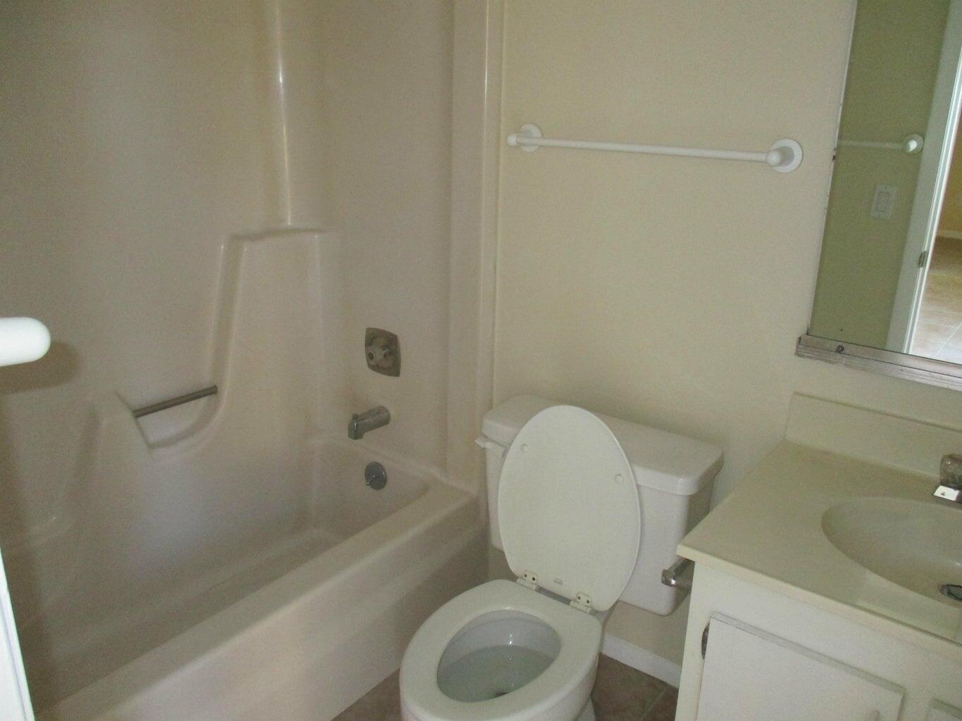 A bathroom featuring a beige tub-shower combo, a white toilet, and a vanity with sink — 825 Center Street # 3c, Jupiter FL 33458, JUPITER, FL