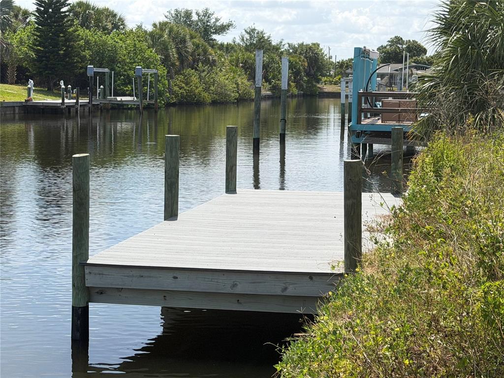 A wooden dock extends into a narrow canal surrounded by lush green vegetation — 17122 MARYDALE ROAD, PORT CHARLOTTE, FL