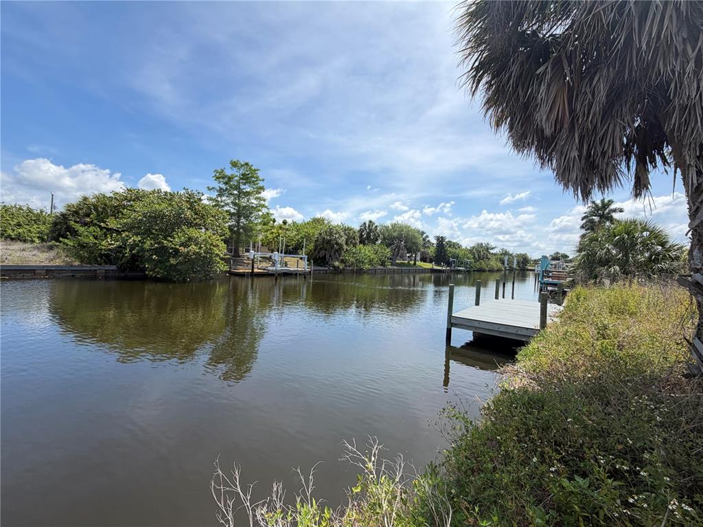 A view of a calm canal with a wooden dock and lush green vegetation — 17122 MARYDALE ROAD, PORT CHARLOTTE, FL