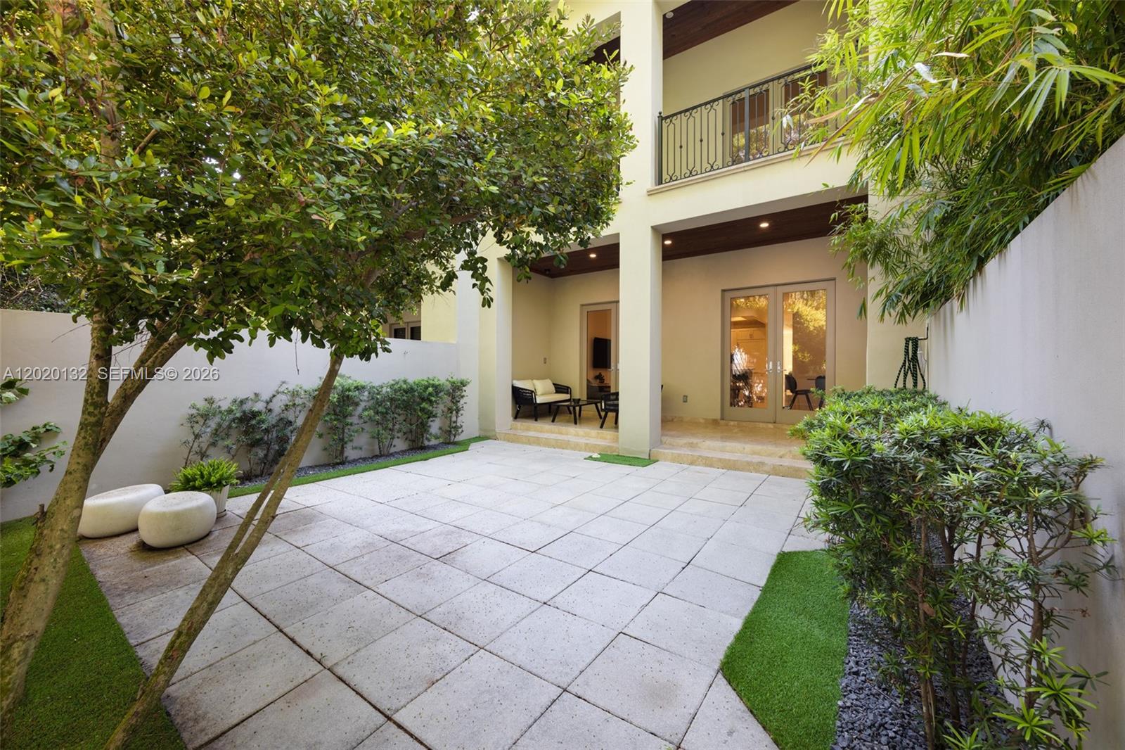 A paved courtyard features a tree, landscaping, and a covered patio with glass doors — 7430 SW 56th Ct, Miami FL 33143, MIAMI, FL