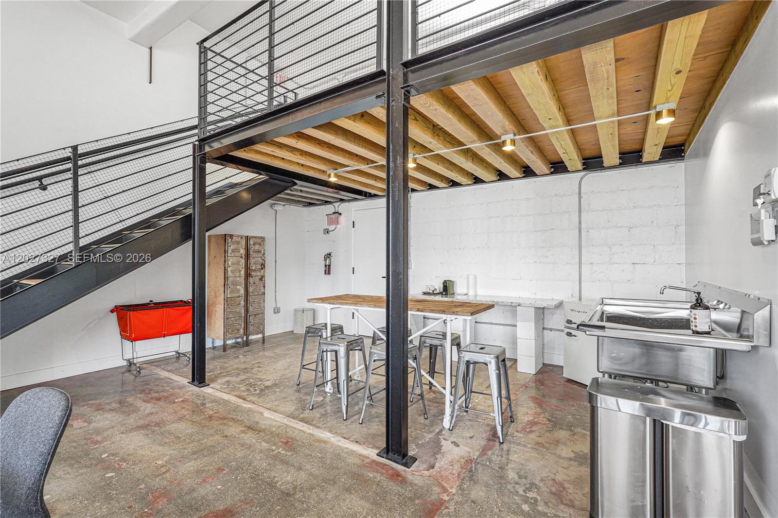 An industrial-style room features a metal staircase, a wooden loft, and a kitchenette area — 798 NW 62nd St, Miami FL 33150, MIAMI, FL