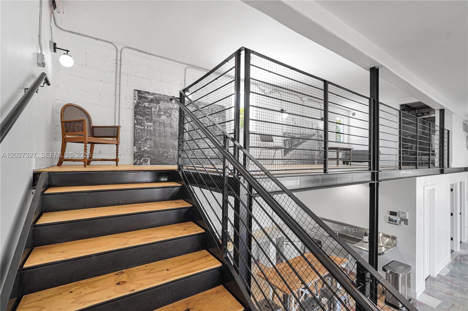 A wooden staircase with black metal railings leads to an industrial-style loft with exposed brick — 798 NW 62nd St, Miami FL 33150, MIAMI, FL