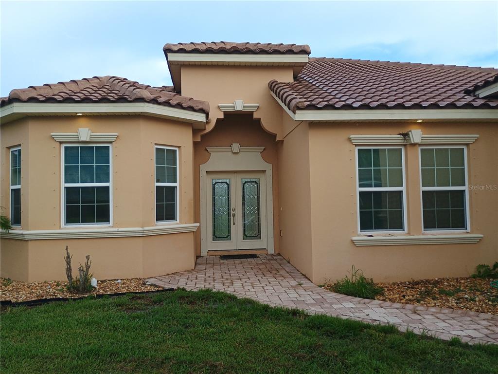 A tan stucco house with a tiled roof and double front doors — 4394 PRESERVATION CIRCLE, MELBOURNE, FL