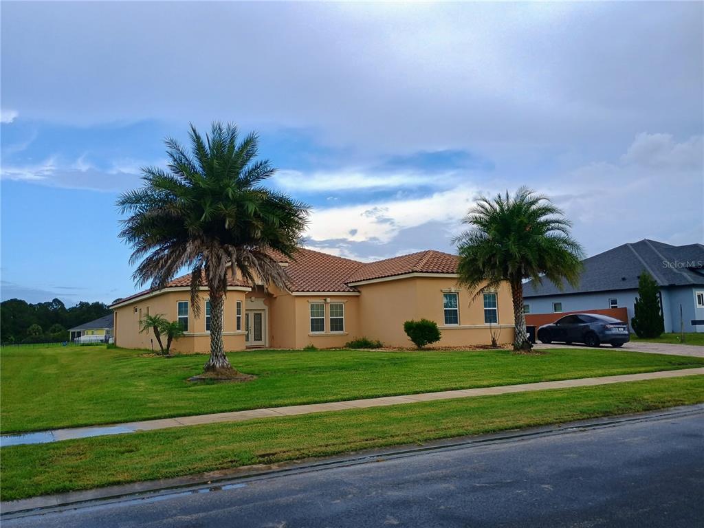 A single-story tan stucco house with a tiled roof and two palm trees in front — 4394 PRESERVATION CIRCLE, MELBOURNE, FL