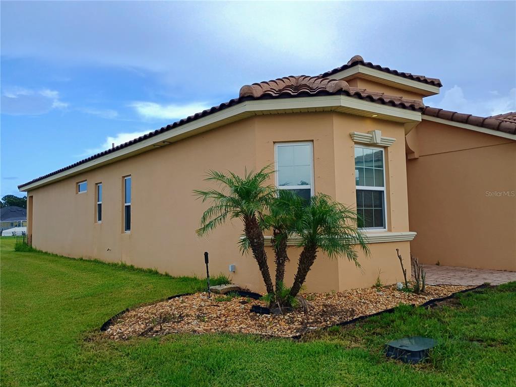 The exterior of a tan stucco house features a small palm tree and tiled roof — 4394 PRESERVATION CIRCLE, MELBOURNE, FL