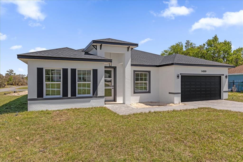 A single-story house with white stucco walls, black trim, and a two-car garage — 14889 SW 24TH CIRCLE, OCALA, FL
