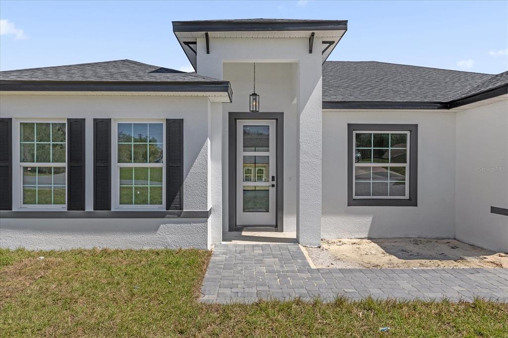 The exterior of a white house features a front entrance with a paved walkway — 14889 SW 24TH CIRCLE, OCALA, FL