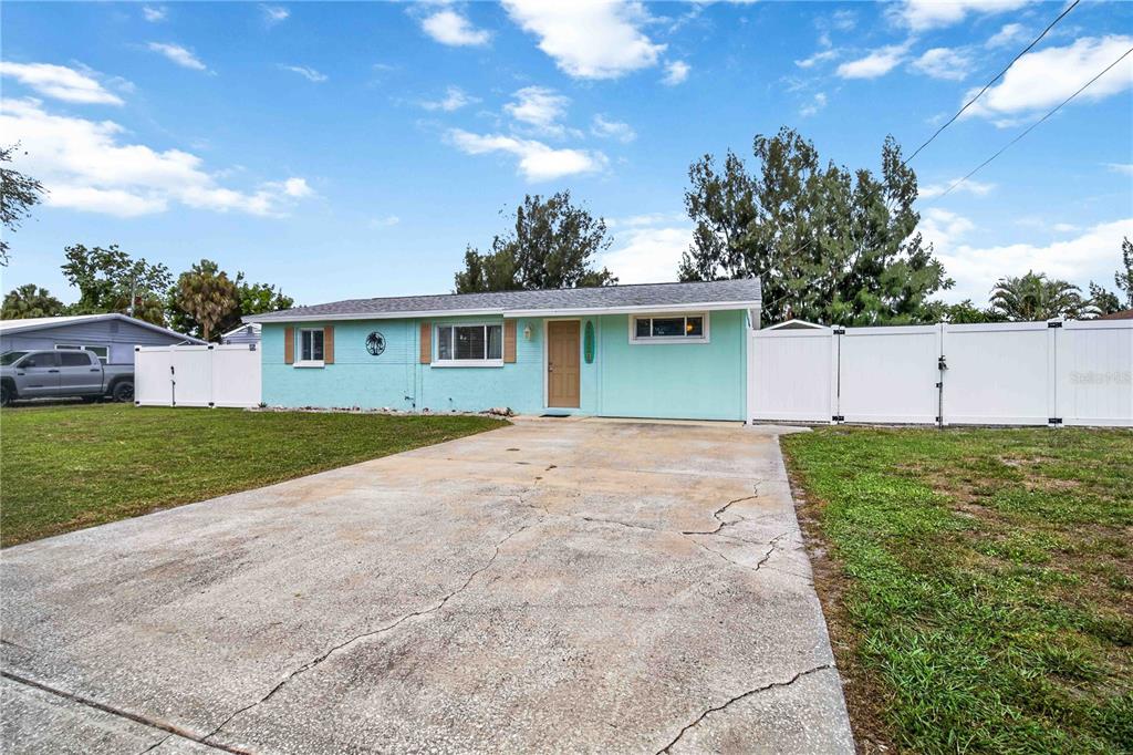 A light blue single-story house with a concrete driveway and white vinyl fencing — 4620 3RD AVENUE W, PALMETTO, FL