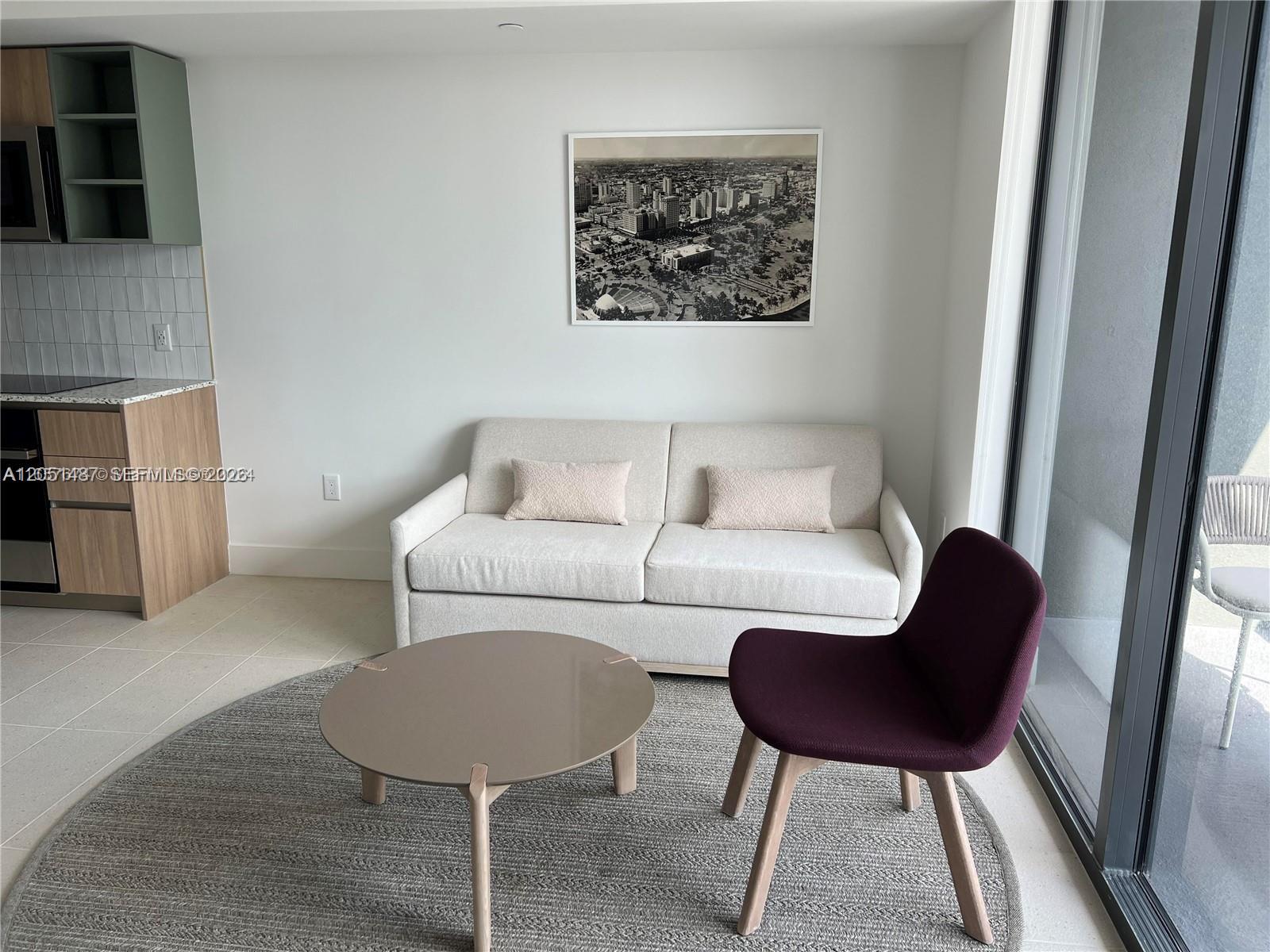 A living room features a beige sofa, a round coffee table, and a purple chair — 159 NE 6th St # 2807, Miami FL 33132, MIAMI, FL