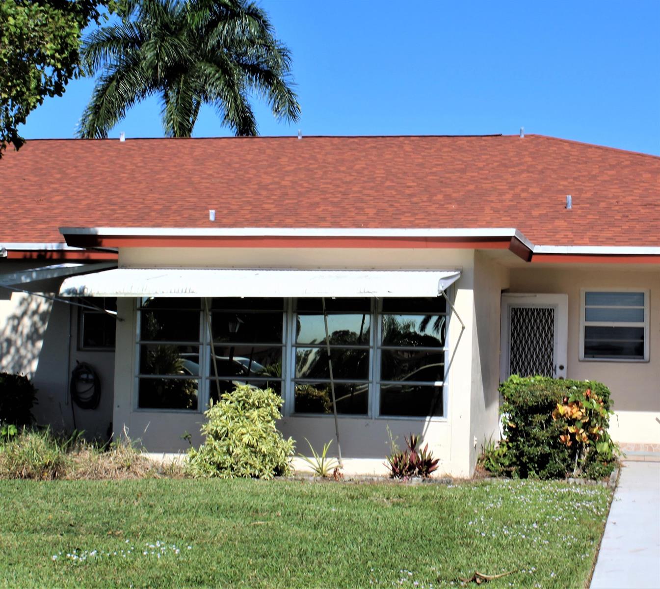 A single-story house with a red shingled roof, white awning, and a front lawn — 4755 NW 3rd Court # C, Delray Beach FL 33445, DELRAY BEACH, FL