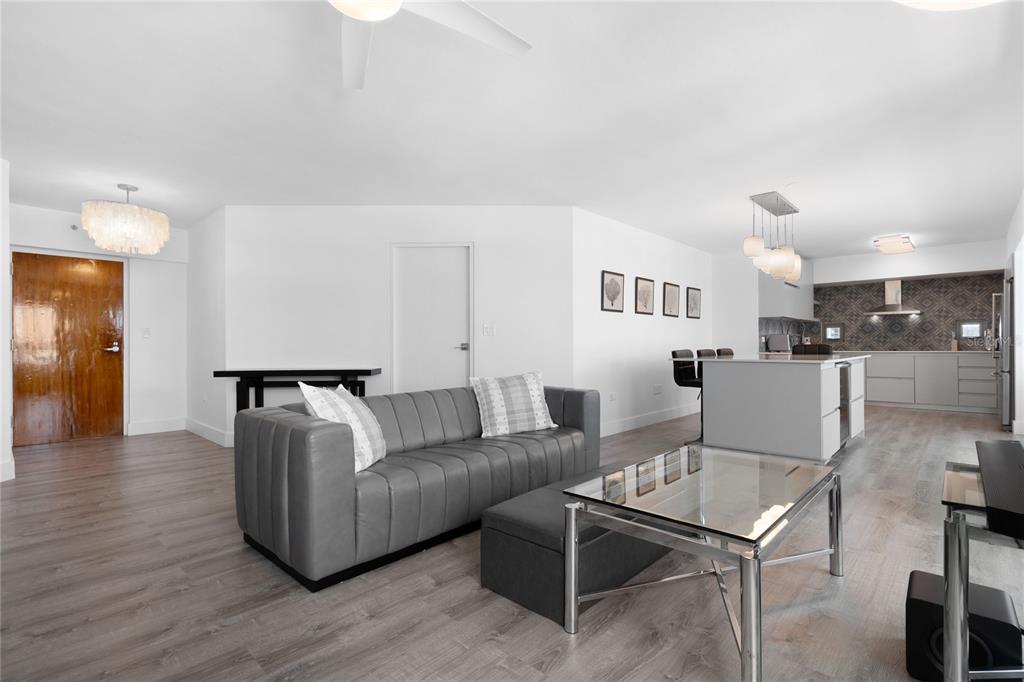A modern open-concept living room and kitchen featuring gray wood flooring and neutral furnishings — 103 AVENIDA JOSE DE DIEGO UNIT 803N, SAN JUAN, PR