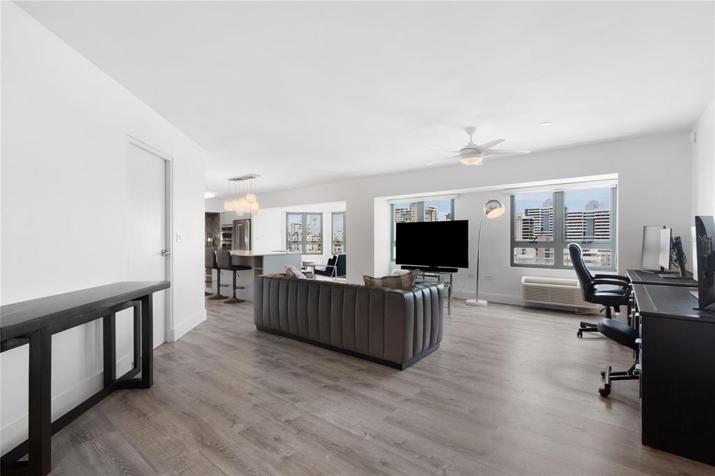 A modern open-concept living room with wood-look flooring, a grey sofa, and a home office — 103 AVENIDA JOSE DE DIEGO UNIT 803N, SAN JUAN, PR