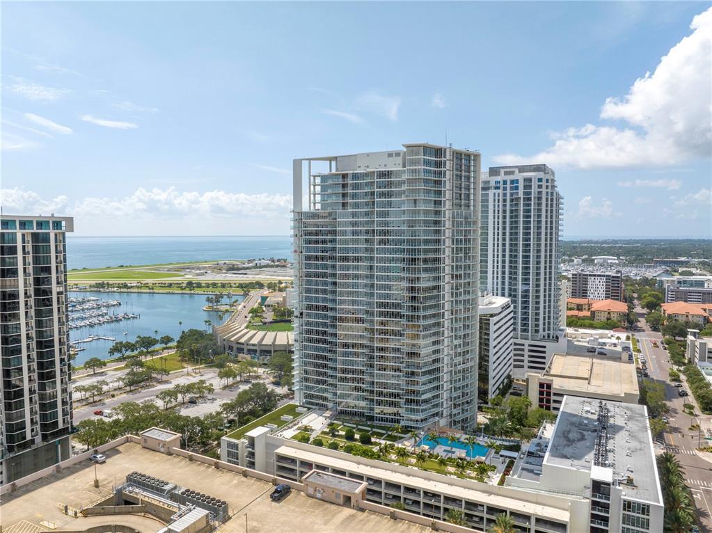 An aerial view shows high-rise apartment buildings, a marina, and a coastal landscape — 175 1ST STREET S UNIT 1006, ST PETERSBURG, FL