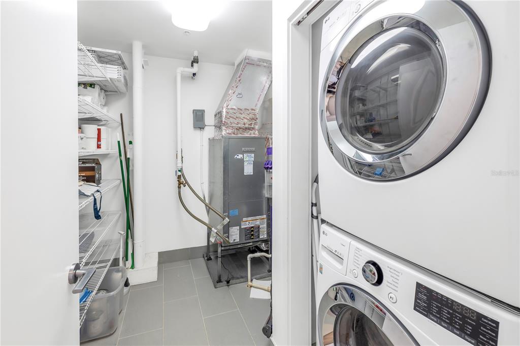 A utility room features a stacked washer and dryer, HVAC unit, and wire shelving — 175 1ST STREET S UNIT 1006, ST PETERSBURG, FL