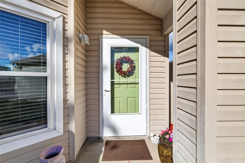 A light-colored house exterior features a front door with a wreath and a side window — 4900 HERON RUN CIRCLE, LEESBURG, FL