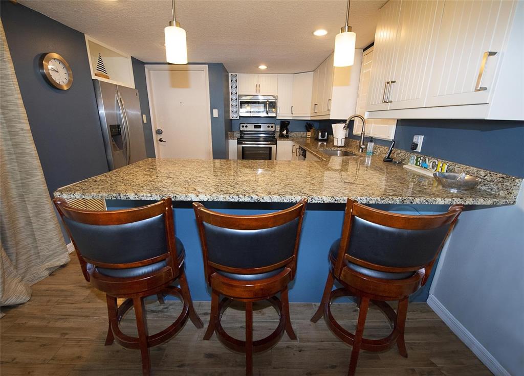 A kitchen features a granite breakfast bar, dark blue walls, and white cabinetry — 1571 S ATLANTIC AVENUE UNIT 105, NEW SMYRNA BEACH, FL