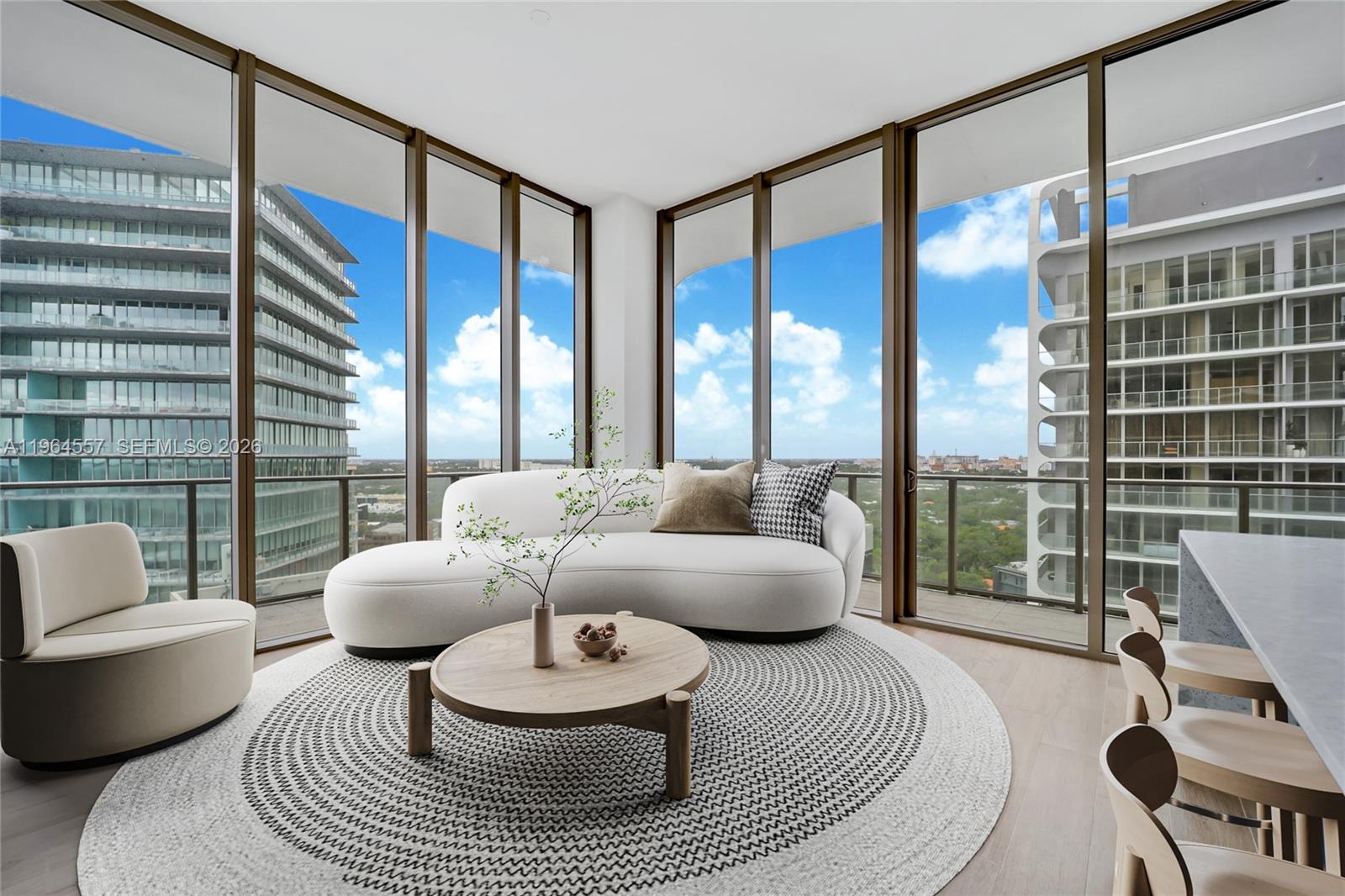 A modern living room features a curved white sofa, round wooden table, and floor-to-ceiling windows — 2655 S Bayshore Dr # 1709, Miami FL 33133, MIAMI, FL