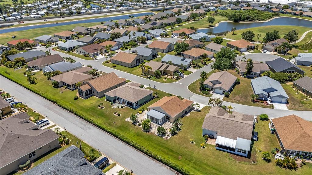 An aerial view shows a suburban neighborhood with single-family homes, paved streets, and a pond — 1924 BODDINGTON TRAIL, PUNTA GORDA, FL