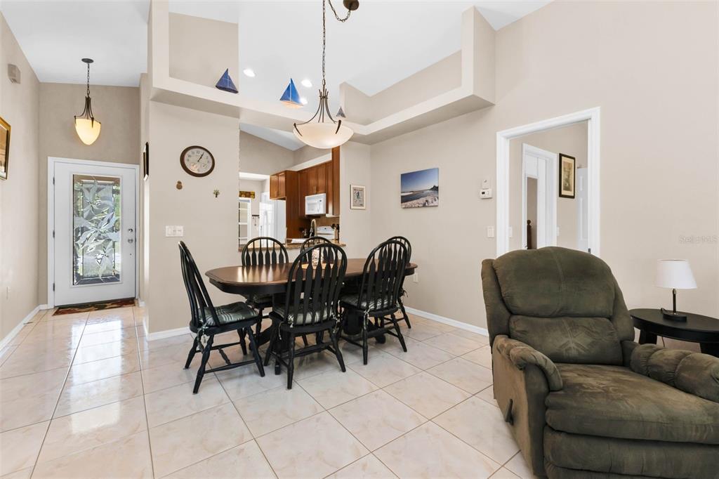 A dining area with a wooden table, black chairs, and tile flooring near an entryway — 1924 BODDINGTON TRAIL, PUNTA GORDA, FL