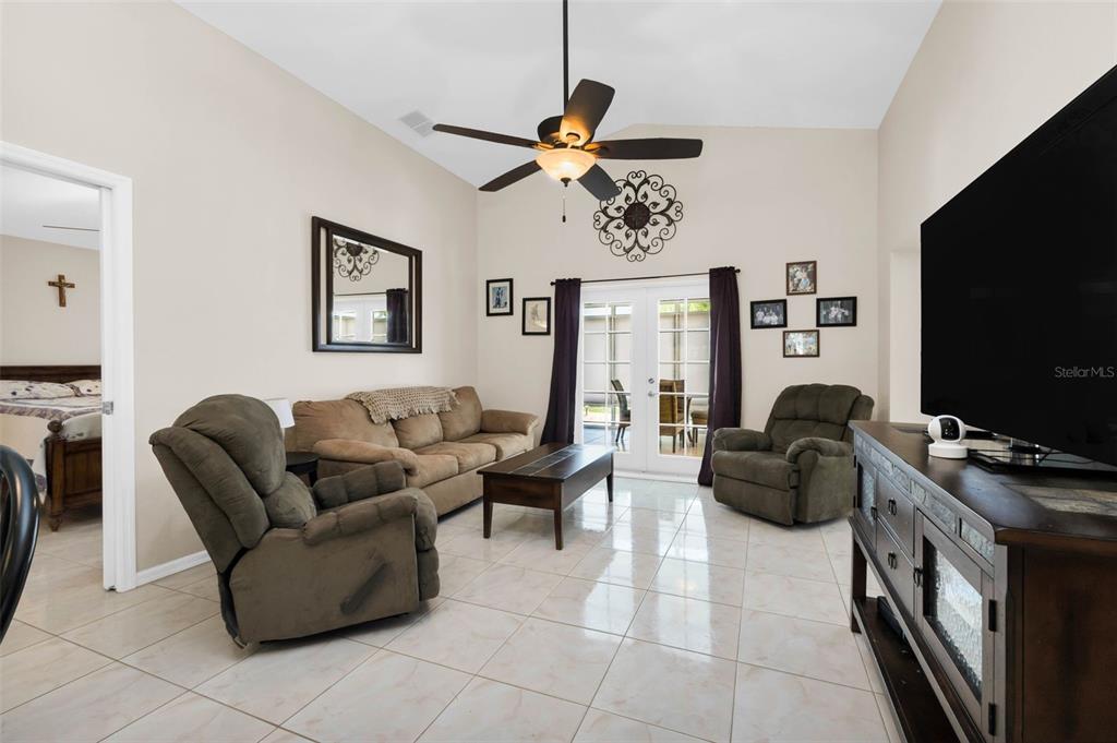 A living room features tile flooring, a ceiling fan, a sofa, two recliners, and glass doors — 1924 BODDINGTON TRAIL, PUNTA GORDA, FL