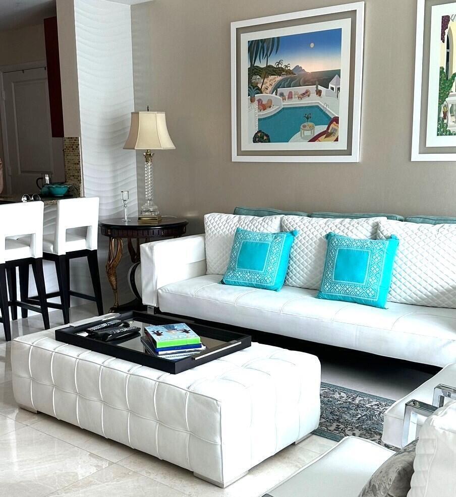 A living room features a white tufted sofa, matching ottoman, and turquoise accent pillows — 1945 S Ocean Drive # 609, Hallandale Beach FL 33009, HALLANDALE BEACH, FL