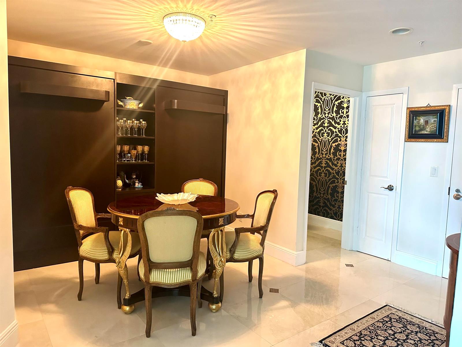 A dining area features a round table with four upholstered chairs and a dark wall unit — 1945 S Ocean Drive # 609, Hallandale Beach FL 33009, HALLANDALE BEACH, FL