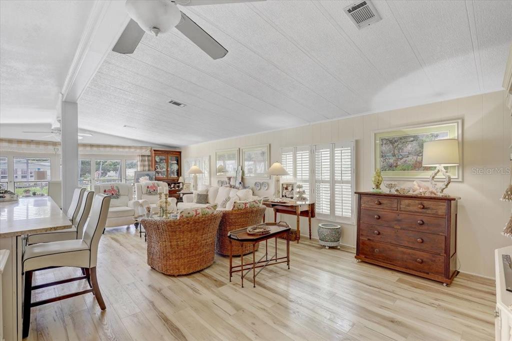 A living room features light wood-look flooring, wicker armchairs, and a wooden dresser — 174 CLUBVIEW DRIVE UNIT 4, SAFETY HARBOR, FL