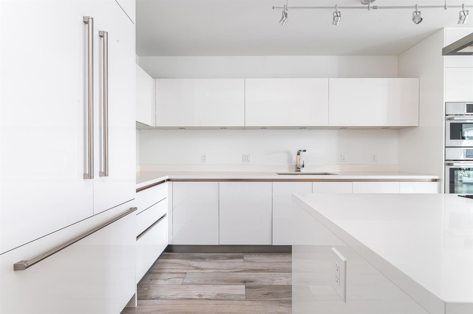 A modern kitchen features white cabinetry, stainless steel appliances, and light wood-look flooring — 155 E Boca Raton Road # 516, Boca Raton FL 33432, BOCA RATON, FL