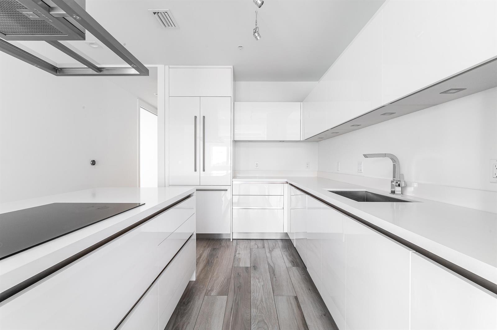 A modern white kitchen features glossy cabinetry, stainless steel appliances, and wood-look flooring — 155 E Boca Raton Road # 516, Boca Raton FL 33432, BOCA RATON, FL