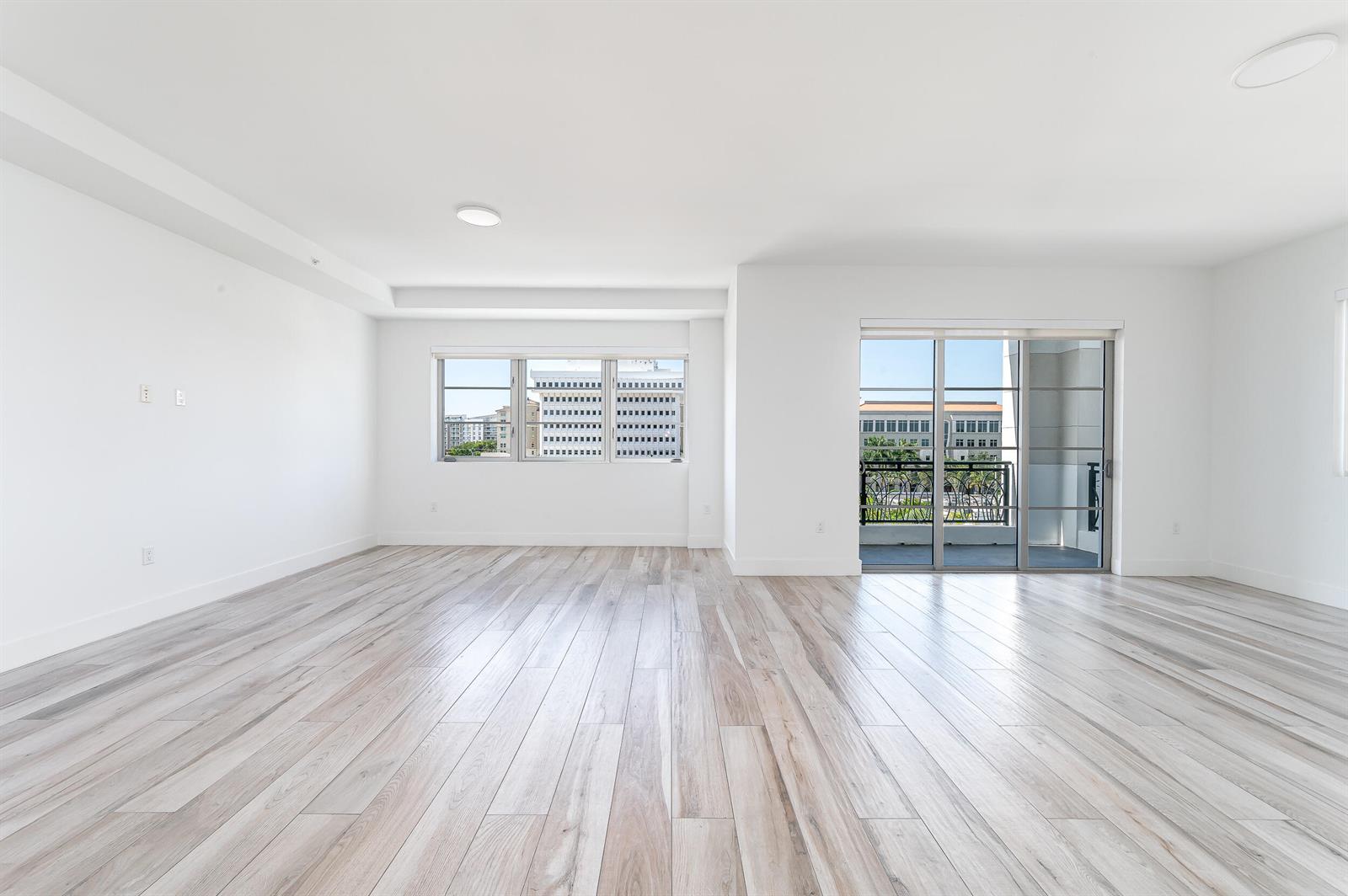 An empty room with light wood-look flooring, white walls, large windows, and a sliding glass door — 155 E Boca Raton Road # 516, Boca Raton FL 33432, BOCA RATON, FL