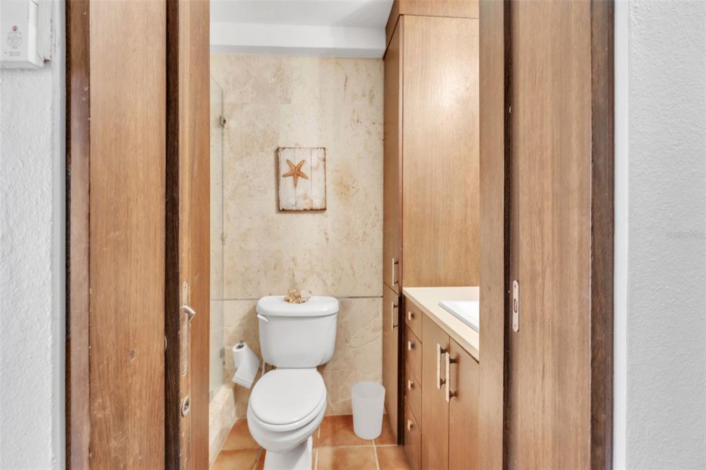 A bathroom features a toilet, a vanity with wooden cabinets, and beige tiled walls — 7 ISLA SAN MARCOS UNIT 7, HUMACAO, PR