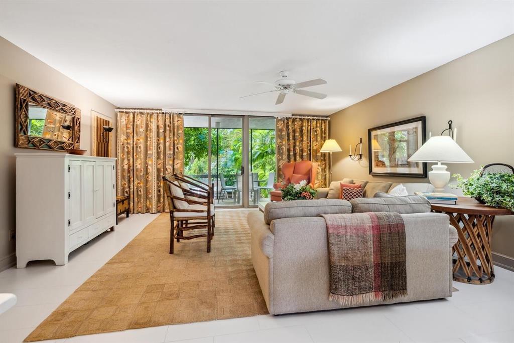 A living room features a beige sofa, a patterned rug, and sliding glass doors to a patio — 840 BAYPORT WAY UNIT 840, LONGBOAT KEY, FL