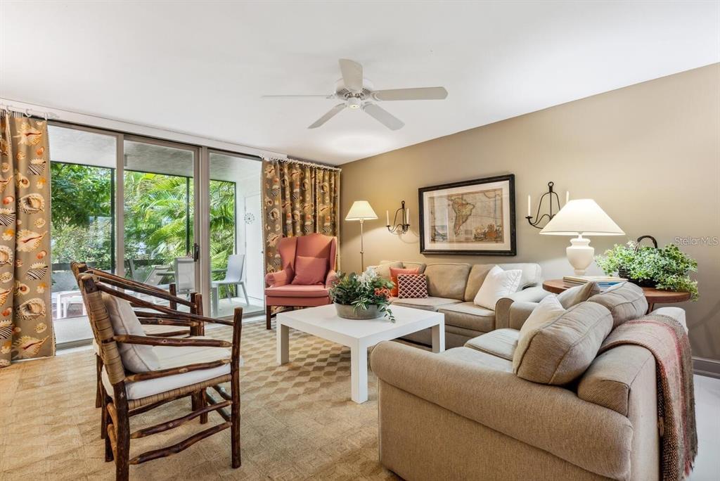 A living room features beige sofas, a pink armchair, a white coffee table, and sliding doors — 840 BAYPORT WAY UNIT 840, LONGBOAT KEY, FL