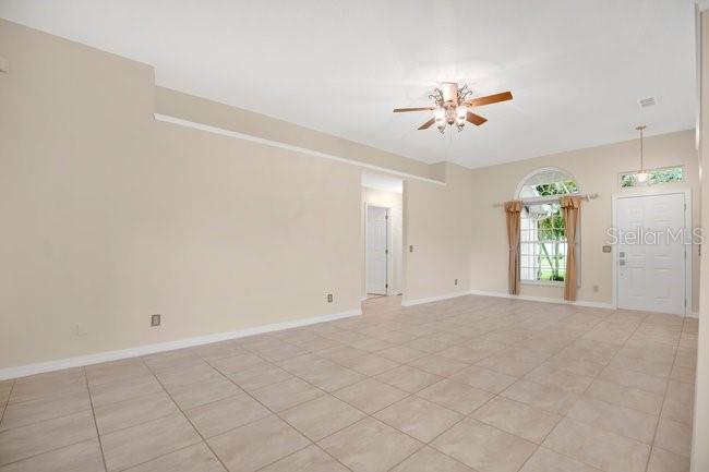 A living room features a wall-mounted television, a dark sofa, and a patterned area rug — 213 MILL SLOUGH ROAD, OVIEDO, FL
