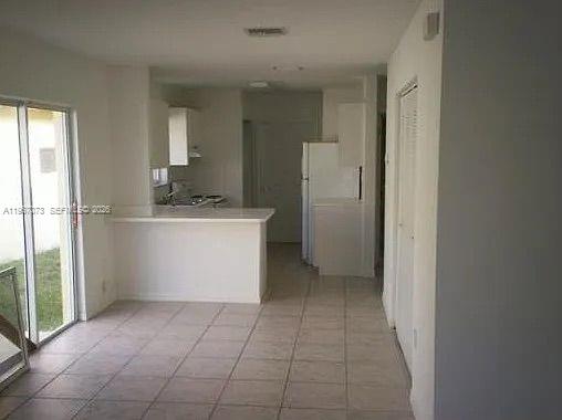A kitchen with white cabinets and a breakfast bar overlooks a tiled dining area — 937 SW 8th Pl, Florida City FL 33034, FLORIDA CITY, FL