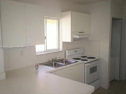 A kitchen features white cabinets, a double sink, and a white electric stove — 937 SW 8th Pl, Florida City FL 33034, FLORIDA CITY, FL