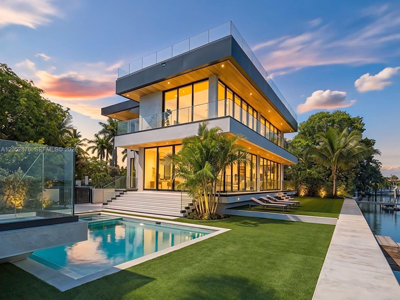 A modern two-story waterfront home features a swimming pool, glass railings, and a landscaped lawn — 1141 N Biscayne Point Rd, Miami Beach FL 33141, MIAMI BEACH, FL