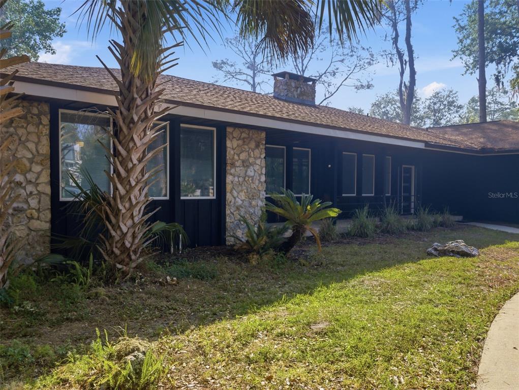 A single-story house with black siding, stone accents, and a palm tree in the front — 6201 SW 37TH WAY, GAINESVILLE, FL