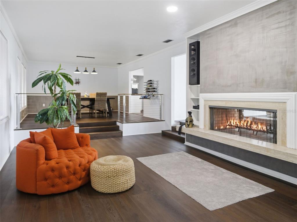 A living room features a fireplace, a tufted orange chair, and a raised dining area — 6201 SW 37TH WAY, GAINESVILLE, FL